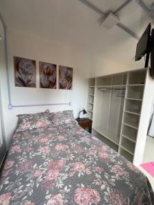 una camera da letto con un letto con copriletto floreale di Containers Schmitz - Kitnet 1 a Florianópolis