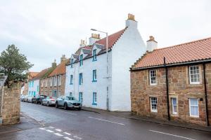 a row of buildings on a street with parked cars at Harbour View Apartment - Crail in Crail