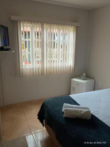 a white bedroom with a bed and a window at Pousada Fonte da Samaritana in Vila Velha