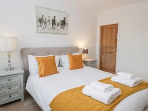 een slaapkamer met een groot wit bed met oranje kussens bij No 2 The Flags in Cartmel