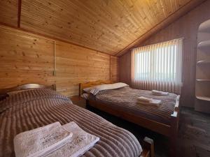 a bedroom with two beds in a wooden cabin at Котедж Краєвид in Yablunytsya