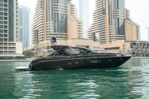 a black boat in the water in front of a city at Yacht Azimut Atlantis 50 in Dubai