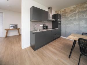 a kitchen with gray cabinets and a wooden table at Kubus Nr. 228 | 4 Pers. in Zeewolde