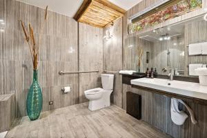 a bathroom with a toilet and a sink and a vase at El Mirador at Speakeasy Hotel - Adults Only in Palm Springs