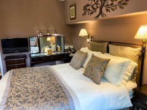 Un dormitorio con una gran cama blanca con espejo. en Stow Lodge Hotel, en Stow on the Wold