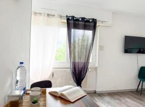 a room with a table with a book and a window at Studio des Trois Frontières in Saint-Louis