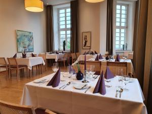 a restaurant with white tables and chairs and windows at Kardinal Schulte Haus in Bergisch Gladbach