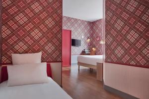 Una habitación de hotel con una cama y un dormitorio con paredes rojas. en Hotel Boris V. by Happyculture, en Levallois-Perret