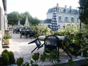 eine Gruppe von Stühlen und Tischen mit Sonnenschirmen auf einer Terrasse in der Unterkunft La Renaudière in Chenonceaux