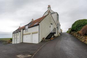 een groot wit gebouw met een trappenhuis naast een weg bij Coastal View - St Monans in Saint Monance