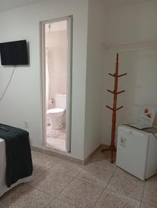 a room with a bathroom with a toilet and a television at Pousada Fonte da Samaritana in Vila Velha