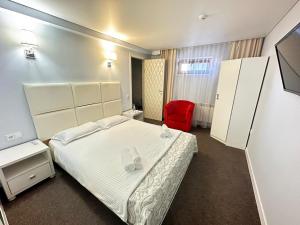 a hotel room with a bed and a red chair at Baiterek Сарайшык 40 in Astana
