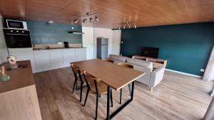 Una cocina y una sala de estar con una mesa y un sofá. en Appartement spacieux tout équipé au coeur de l'avesnois, en Trélon