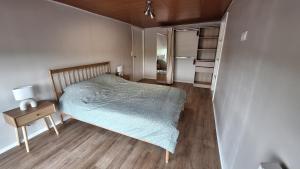 Un dormitorio pequeño con una cama y un refrigerador. en Appartement spacieux tout équipé au coeur de l'avesnois, en Trélon