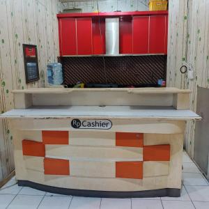 a cashier counter in a kitchen with red cabinets at Nusantara Center Point By Reccoma in Kayuringin