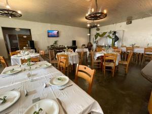 a dining room with tables and chairs with white table linen at Pousada refúgio do lago in Lages