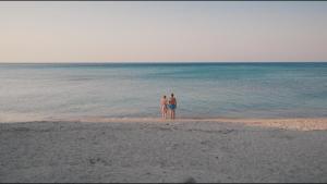 dos personas de pie en la playa mirando al océano en Radisson Blu Resort & Spa Cesme, en Cesme