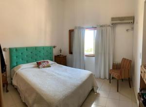 een slaapkamer met een bed met een groen hoofdeinde en een raam bij Casa Maru in Villa Carlos Paz +4 foto's