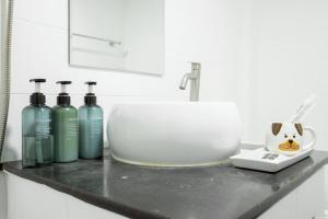 een badkamerkastje met een wastafel en vier flessen bij Cosy Lodge MRT Phra Ram 9 in Bangkok +28 foto's