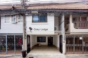 een wit gebouw met een bord waarop 'gezellige lodge' staat bij Cosy Lodge MRT Phra Ram 9 in Bangkok