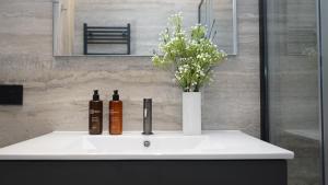 a bathroom sink with two bottles and a vase with flowers at Be Mate Citylife in Milan