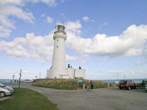 a white lighthouse on a hill next to the ocean at Jenny Wren in Flamborough