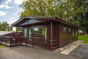 Una gran cabaña de madera con una gran ventana. en Birch Lodge 13 with Hot Tub, en Newton Stewart