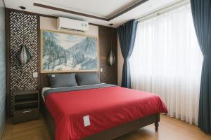 a bedroom with a red bed with a painting on the wall at Lagoon Homestay Hoi An in Hoi An
