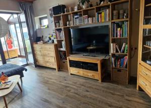 een woonkamer met een grote televisie en boekenplanken bij Ferienhaus Rhönblick in Bischofsheim an der Rhön