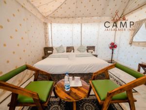 a room with a bed and two chairs and a table at Camp Inn Jaisalmer Resort in Jaisalmer
