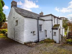 een oud wit huis met een dak bij Low Lane Cottage in Crosby Garrett