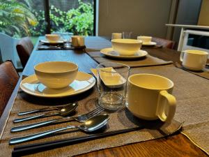 a wooden table topped with plates and cups and silverware at ERUMAYA Resort in Motobu