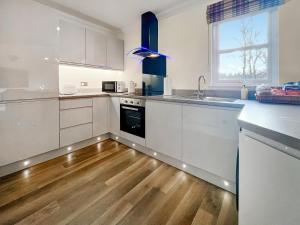 a kitchen with white cabinets and a wooden floor at Dee View Apartment in Banchory