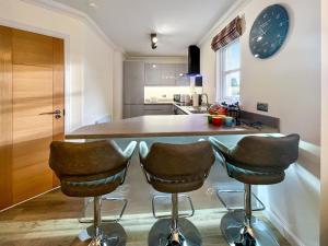 a kitchen with two bar stools and a clock on the wall at Dee View Apartment in Banchory