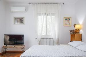 a white bedroom with a bed and a television at Apartment with Free Parking Easy Access to Venice in Mestre