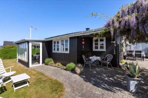 a black house with a table and chairs in the yard at Lovely Summerhouse By The Beach in Karrebæksminde