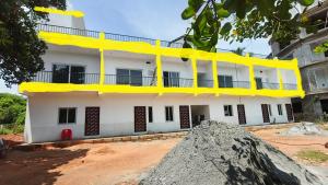 een wit gebouw met gele accenten ervoor bij La Nature Retreat in Kuilapayam