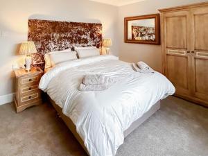 een slaapkamer met een groot wit bed en een houten kast bij Swaleside Cottage in Topcliffe