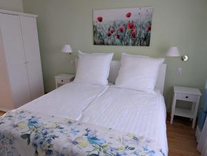 ein Schlafzimmer mit einem Bett mit weißen Laken und roten Blumen in der Unterkunft Ferienhaus MAWO 4 Sterne in Andernach