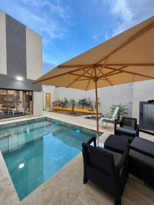 a swimming pool with two chairs and an umbrella at Villa 2 Évasion Urbaine, 3 Chambres, à 20 min de Rabat in Sidi Yahia az Zaʼer
