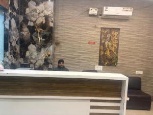 Ein Mann sitzt vor einer Mauer in der Unterkunft Hotel Zirakpur ZKR in Zirakpur + 1 Foto