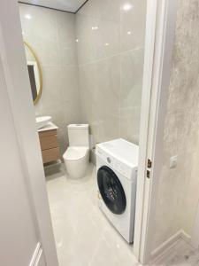 een wasmachine in een badkamer met toilet bij Кокшебель Жк in Astana +9 foto's