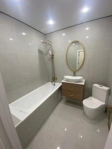 een badkamer met een bad, een toilet en een spiegel bij Кокшебель Жк in Astana