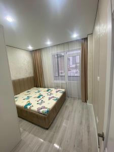 een slaapkamer met een bed en een raam bij Кокшебель Жк in Astana
