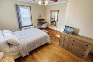 ein Schlafzimmer mit einem Bett und einem Fernseher auf einer Holzkommode in der Unterkunft Suites On Chocolate - The Hershey House in Hershey