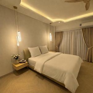 Un dormitorio con una cama blanca grande y una ventana en The Escape Kamala, en Kamala Beach