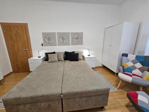 ein großes Bett in einem Zimmer mit 2 Stühlen in der Unterkunft Harmonia Budget apartman in Dunajská Streda