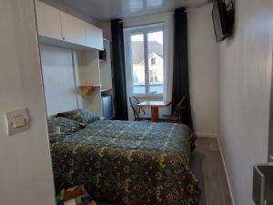 een kleine kamer met een bed en een raam bij Paisible in Les Pieux