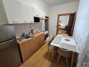 eine kleine Küche mit einem Tisch, einer Spüle und einem Kühlschrank in der Unterkunft Harmonia Budget apartman in Dunajská Streda + 8 Fotos