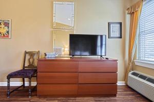 einen TV auf einer Kommode mit einem Stuhl in der Unterkunft Suites On Chocolate - The Theater in Hershey